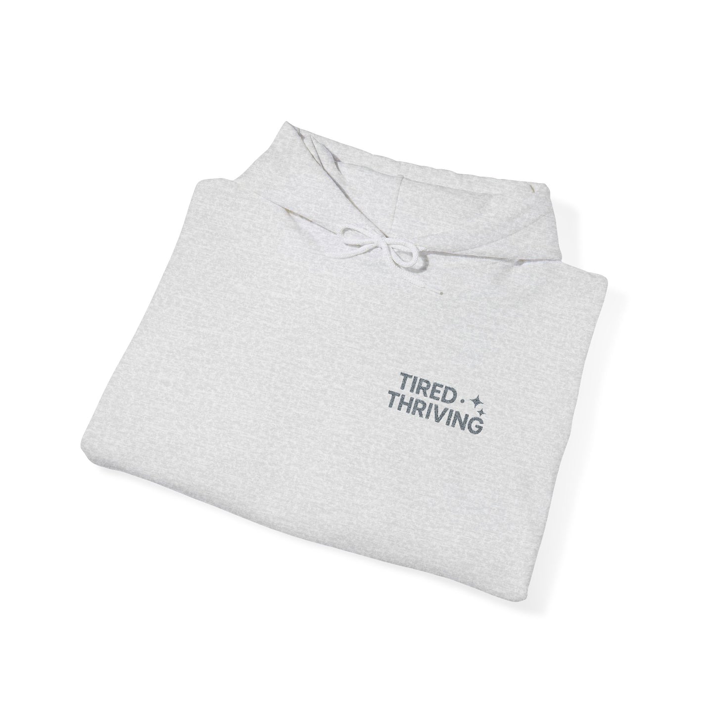 Minimal “Tired + Thriving” Embodied hoodie. Cozy fleece, unisex fit, durable chest graphic—everyday streetwear for busy days that still thrive.